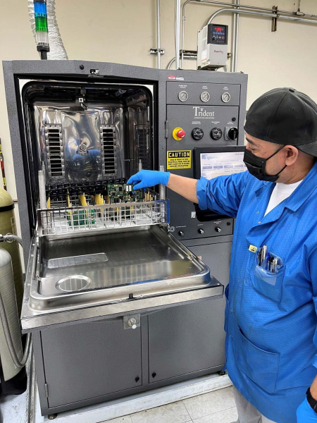 An employee places circuit board in an ionic cleaning machine