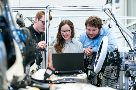Three people around a computer