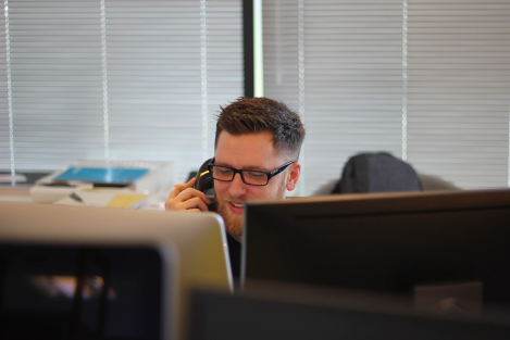 Person on the phone infront of the computer 